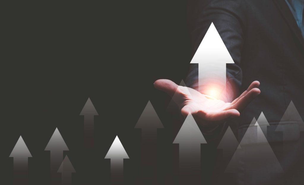 Business growth concept with hand holding upward arrows, symbolizing success and progress.
