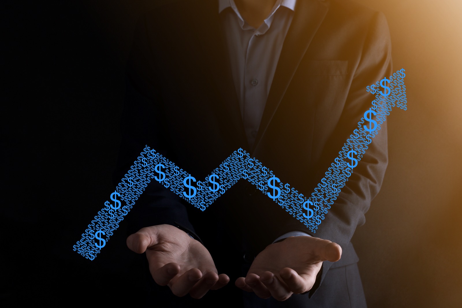 A businessman holding a rising profit graph made of dollar signs, symbolizing business profits growth.